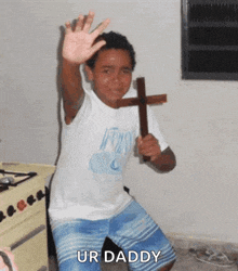 a young boy is holding a wooden cross and waving his hand .