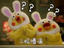 two stuffed chickens dressed as rabbits are standing next to each other and making a surprised face .