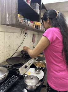 a woman in a pink shirt is cooking on a stove that says ' lg ' on the front