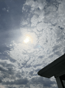 the sun is shining through the clouds above the roof of a house