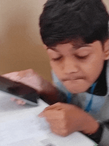 a young boy with a blue lanyard around his neck is looking at a piece of paper