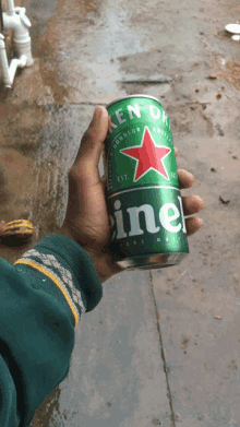 a person holding a green can of heineken beer