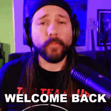 a man with long hair and a beard wearing headphones and a microphone says welcome back