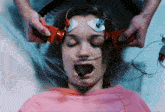 a woman in a pink shirt is laying in a hospital bed with an oxygen mask on her head