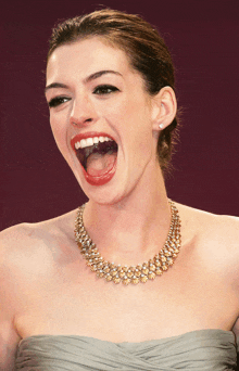 a woman wearing a necklace is laughing with her mouth wide open