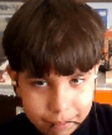 a close up of a young boy 's face with a black shirt on