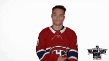 a man in a canadiens jersey is looking at his watch in front of a sign that says wednesday night hockey