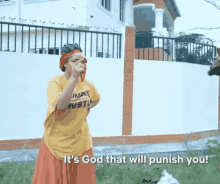 a woman in a yellow shirt and orange skirt is standing in front of a fence and talking to a man .