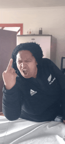 a person wearing a black all blacks shirt giving the middle finger