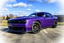 a purple dodge challenger is parked in a parking lot with a blue sky in the background