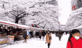 a woman wearing a mask walks down a snowy street in front of a sign that says ' tokyo '