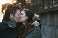 a man and a woman kissing in front of a building