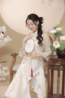 a woman sits in a chair holding a fan and smiling