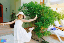 a little girl in a white dress and hat is standing in front of a tree with the word momento behind her