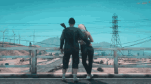 a man and a woman are standing on a bridge looking at the mountains