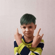 a young boy with green hair is making a horn sign