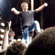 a man in a black shirt is dancing on a stage in front of a crowd