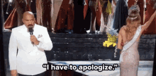 a man with a microphone says " i have to apologize " next to a woman in a dress