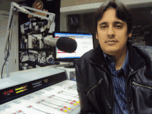 a man in a black jacket stands in front of a microphone in a studio