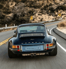 a blue porsche is driving down a curvy road