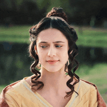 a woman with curly hair wearing a yellow shirt