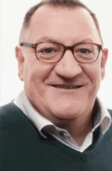 a man wearing glasses and a green shirt smiles for the camera