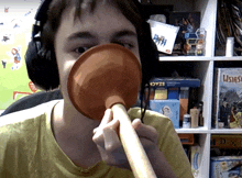 a man wearing headphones holds a plunger in his mouth in front of a stack of usings games