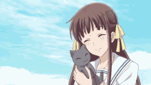 a girl in a sailor suit is holding a cat in her arms .