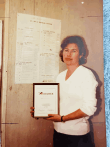 a woman holds a framed certificate that says charter