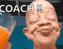 a bald man is smiling with the words coach written on his forehead