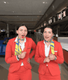 two women in red suits are standing next to each other in front of a counter with the number 29 on it