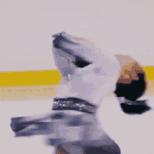 a figure skater is doing a trick on the ice while wearing a white outfit .