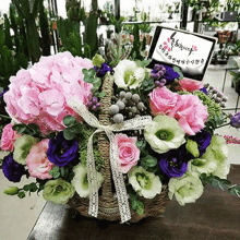 a basket filled with pink and purple flowers and a card .