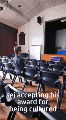 a man sits in an auditorium with the words " sej accepting his award for being cultured " at the bottom