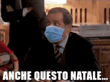 a man in a suit and tie wearing a face mask with the words anche questo natale below him