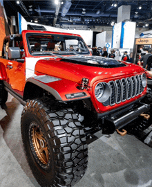 a red and white jeep is on display at a car show