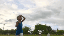 a young boy in a blue tank top runs in a park