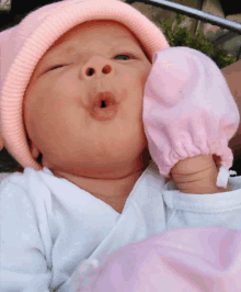 a baby wearing a pink hat and a pink mitten