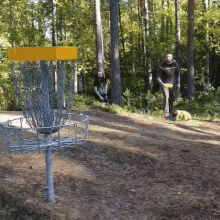 two men are playing frisbee golf in the woods and one of them is wearing a t-shirt that says ' a '