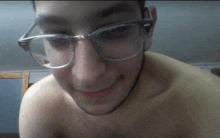 a shirtless man wearing glasses is smiling