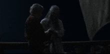 two men are standing next to each other in a dark room holding hands