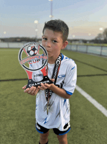 a young boy is holding up a trophy that says kansas city champions cup