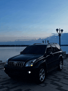 a black toyota suv is parked near a body of water at night