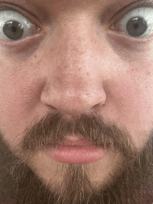 a close up of a man 's face with a beard making a funny face