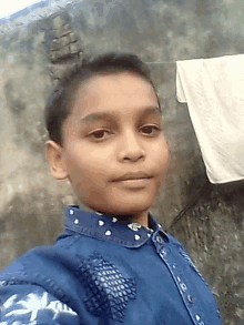 a young boy in a blue shirt takes a selfie in front of a brick wall