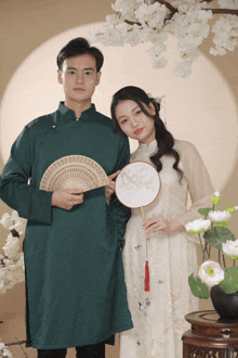 a man holding a fan and a woman holding a fan standing next to each other