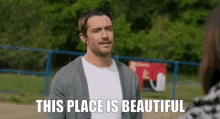 a man is standing in front of a fence with the words " this place is beautiful " above him