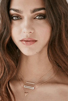 a close up of a woman 's face wearing three necklaces