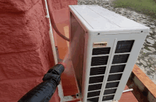 a person is spraying water on a white air conditioner