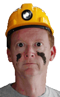 a man wearing a hard hat with a flashlight on it has dirt on his face